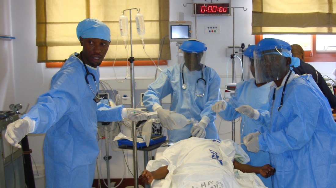 Emergency physicians in protective equipment resuscitating a patient